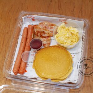 American Breakfast: Pancakes and scrambled eggs with sausages, bacon and maple syrup