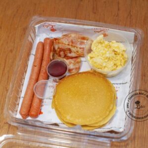 American Breakfast: Pancakes and scrambled eggs with sausages, bacon and maple syrup
