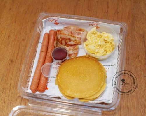 American Breakfast: Pancakes and scrambled eggs with sausages, bacon and maple syrup
